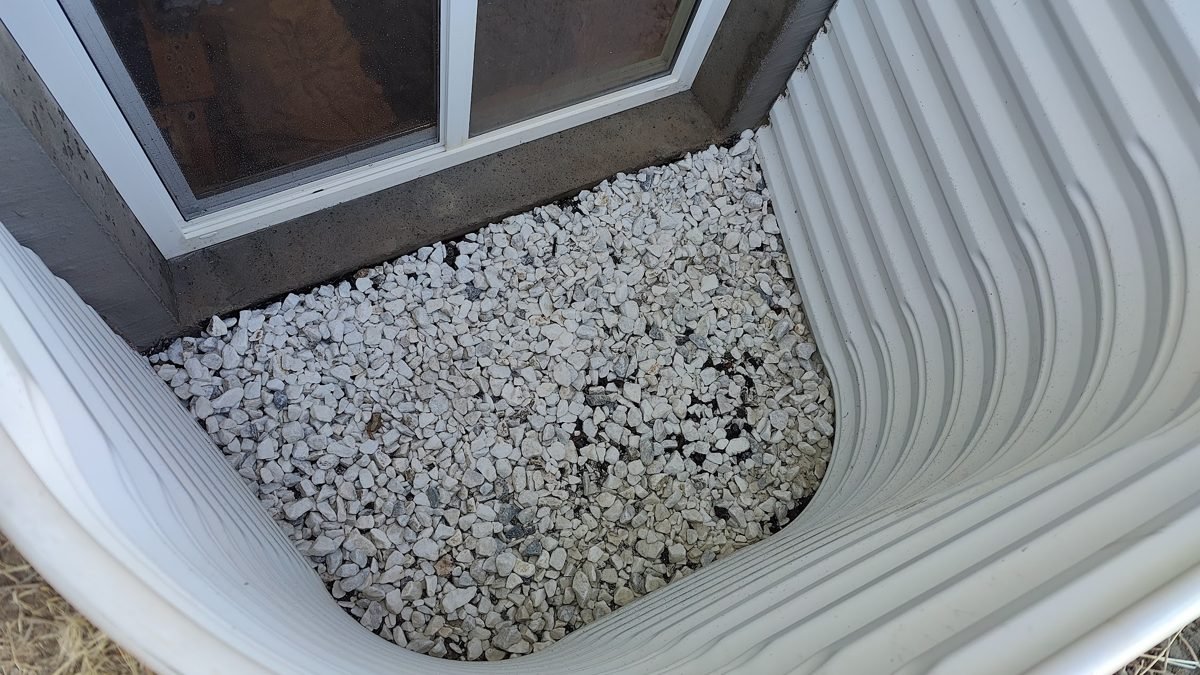 Window well with fresh gravel and clean glass after WellKeepers service